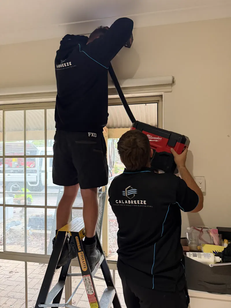 Two Calabreeze air-conditioning installers fitting an indoor unit