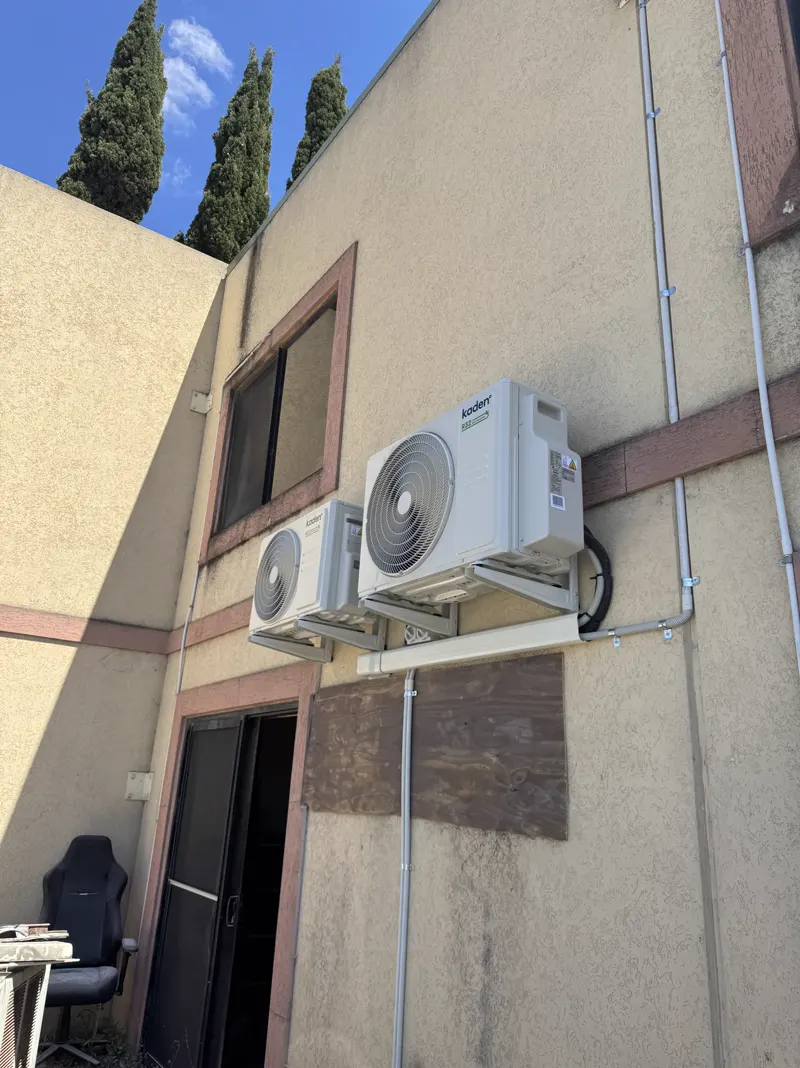 Multi-head air-conditioning outdoor units mounted on a rendered wall